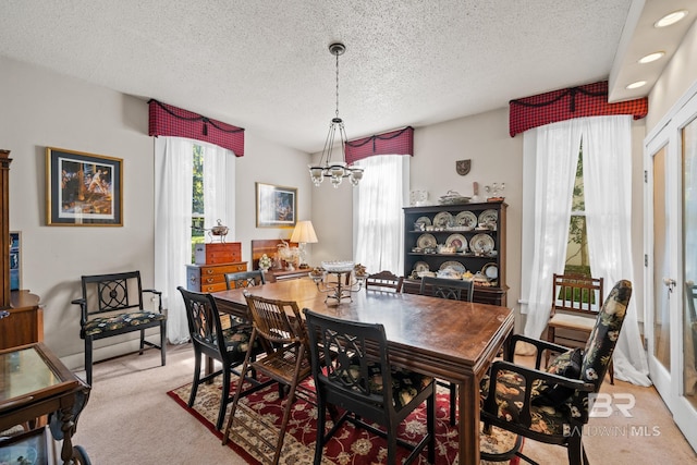 dining area featuring a chandelier, light colored carpet, and a textured ceiling