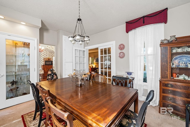 dining room with french doors, light colored carpet, and a textured ceiling