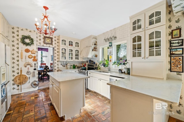 kitchen with sink, an inviting chandelier, tasteful backsplash, pendant lighting, and a kitchen island