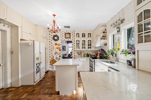 kitchen featuring electric stove, a notable chandelier, white fridge with ice dispenser, a kitchen island, and hanging light fixtures