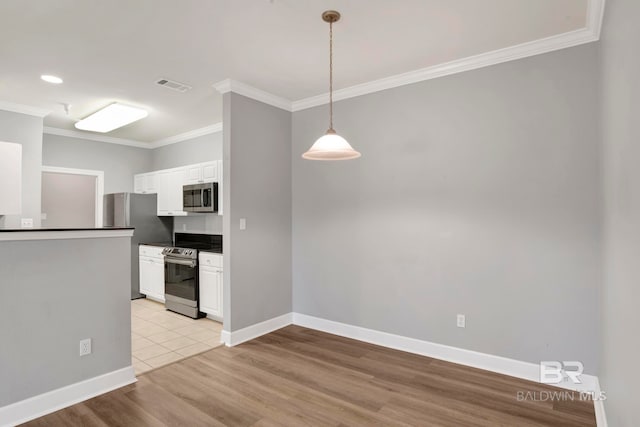 kitchen with appliances with stainless steel finishes, ornamental molding, light hardwood / wood-style floors, white cabinetry, and hanging light fixtures