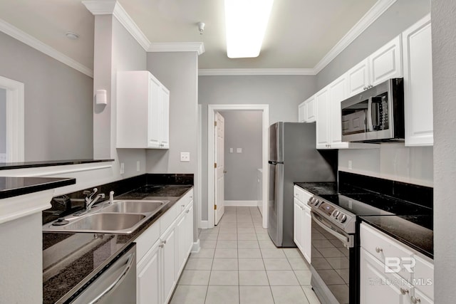 kitchen featuring stainless steel appliances, sink, light tile patterned floors, dark stone countertops, and white cabinetry