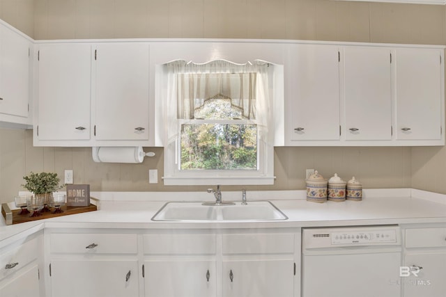 kitchen with white cabinetry, white dishwasher, and a sink