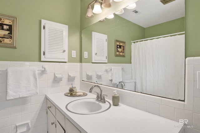 bathroom with visible vents, tile walls, a wainscoted wall, and vanity