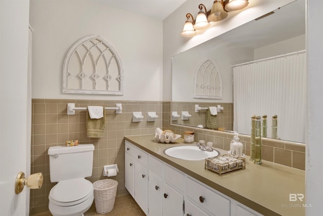 bathroom with a wainscoted wall, toilet, tile walls, and vanity