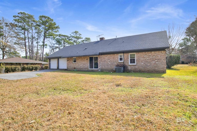 rear view of property with brick siding, driveway, an attached garage, and a yard