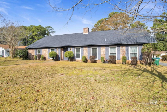 single story home featuring brick siding, a chimney, a front yard, and roof with shingles