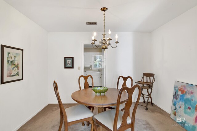 dining space featuring a notable chandelier, light colored carpet, visible vents, and baseboards