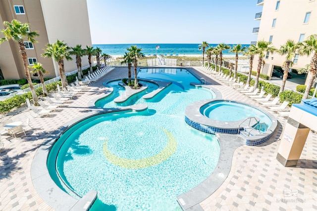 view of pool with a patio, a water view, and a community hot tub