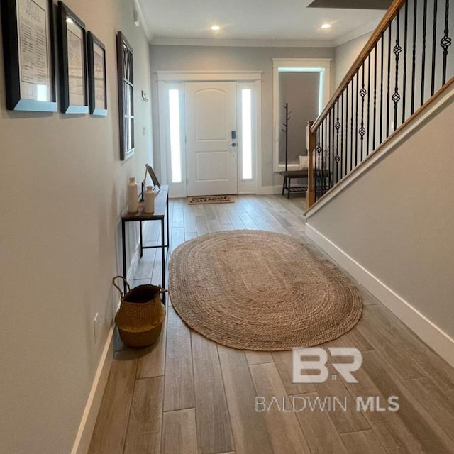 entrance foyer with baseboards, wood finished floors, and crown molding