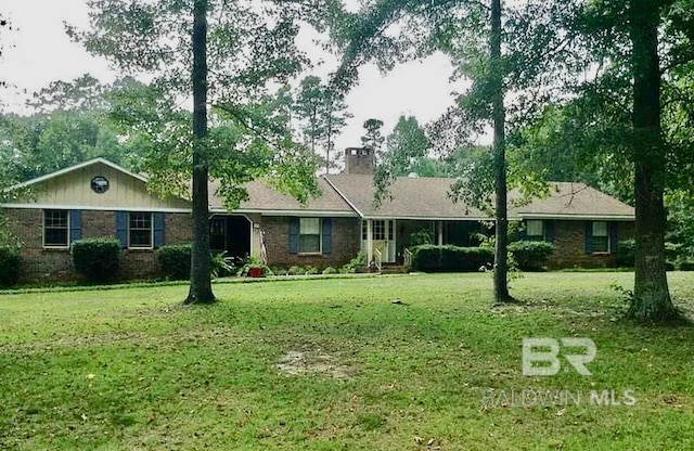 single story home featuring brick siding, a chimney, and a front lawn