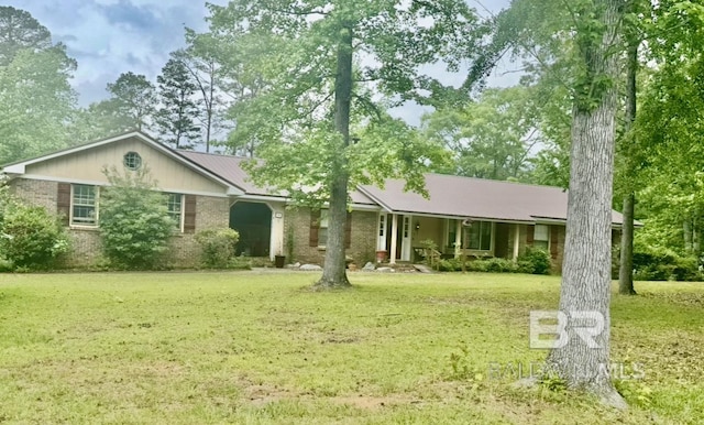 single story home with brick siding, covered porch, a front yard, and metal roof