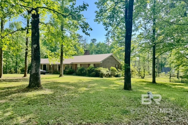 ranch-style home with a chimney and a front lawn