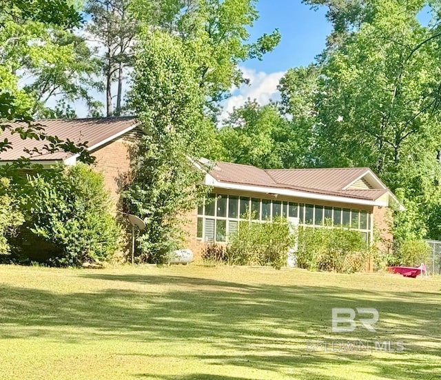 rear view of property with a lawn, metal roof, and a sunroom
