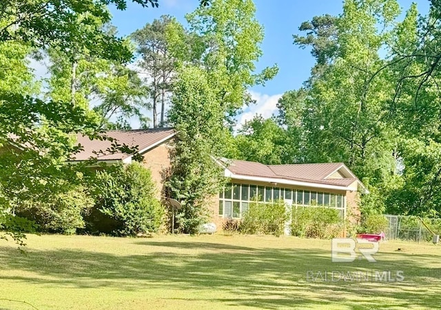 back of house featuring fence, a yard, and metal roof