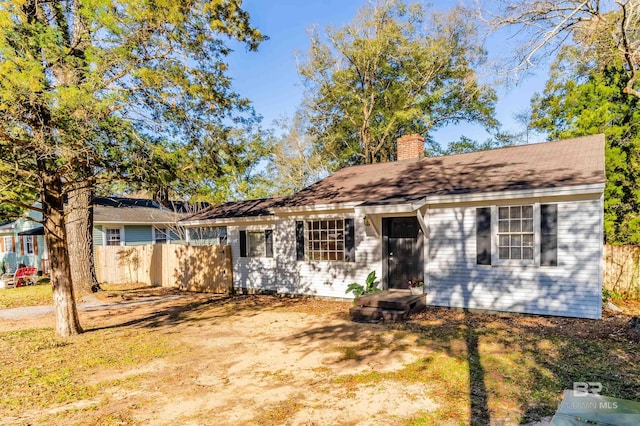 ranch-style home featuring a chimney and fence