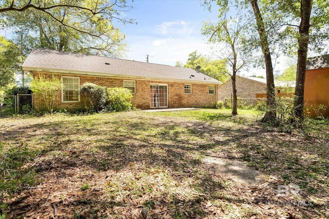 back of house featuring brick siding and fence
