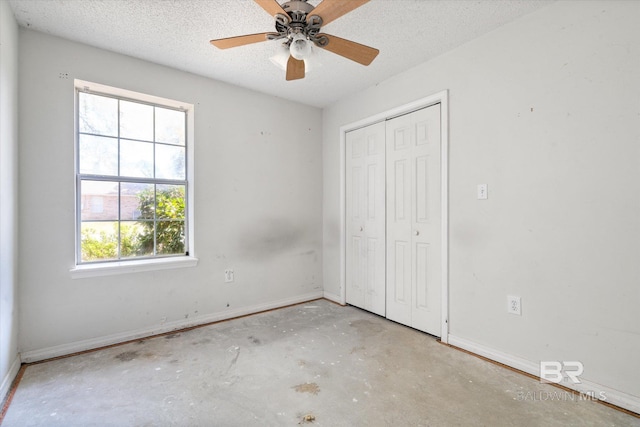unfurnished bedroom with ceiling fan, a textured ceiling, baseboards, unfinished concrete floors, and a closet