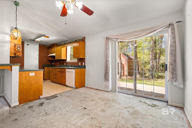 kitchen featuring dark countertops, a sink, concrete floors, vaulted ceiling, and pendant lighting
