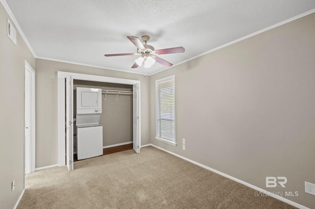 unfurnished bedroom featuring light carpet, stacked washer and dryer, ceiling fan, a textured ceiling, and a closet