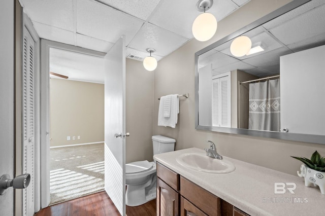 bathroom featuring vanity, a drop ceiling, toilet, and wood-type flooring