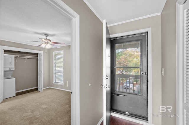 interior space with carpet flooring, ceiling fan, stacked washing maching and dryer, a textured ceiling, and ornamental molding