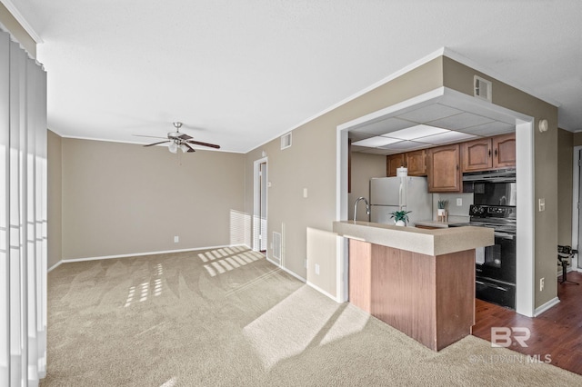 kitchen featuring black electric range oven, crown molding, kitchen peninsula, and white refrigerator