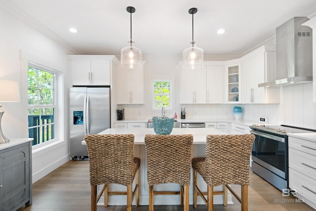 kitchen with white cabinets, appliances with stainless steel finishes, wall chimney exhaust hood, and tasteful backsplash