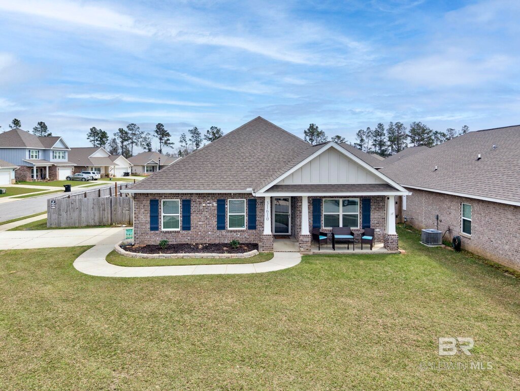 craftsman inspired home featuring brick siding, a front lawn, central AC, and a shingled roof
