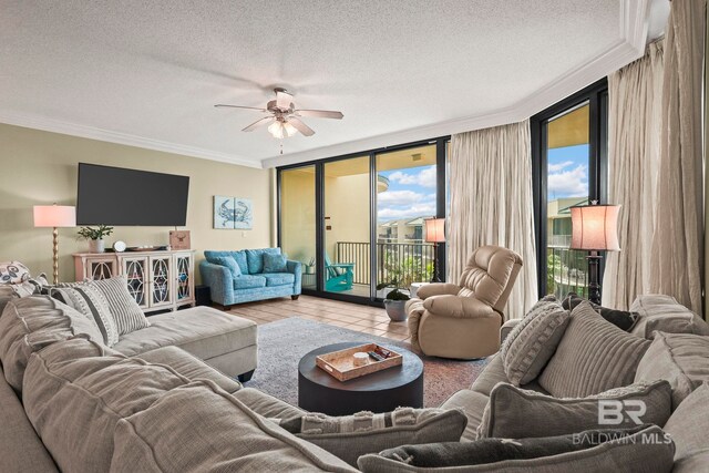 living room with a textured ceiling, ornamental molding, ceiling fan, and plenty of natural light