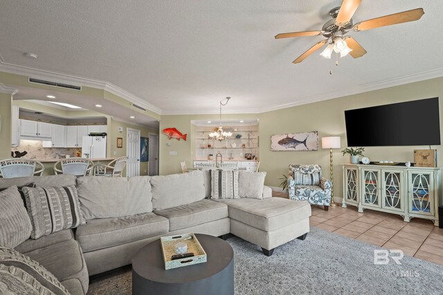 living room with ceiling fan with notable chandelier, a textured ceiling, light tile patterned floors, and ornamental molding