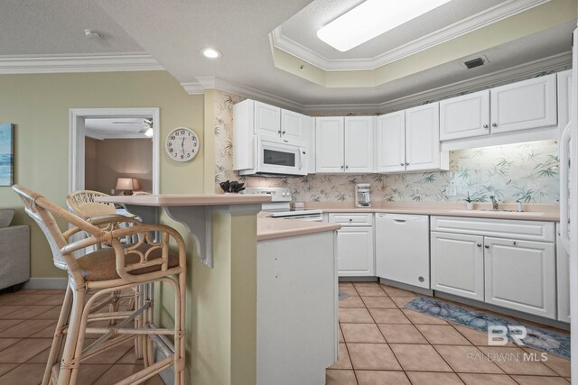 kitchen featuring a kitchen breakfast bar, ornamental molding, white appliances, and white cabinetry