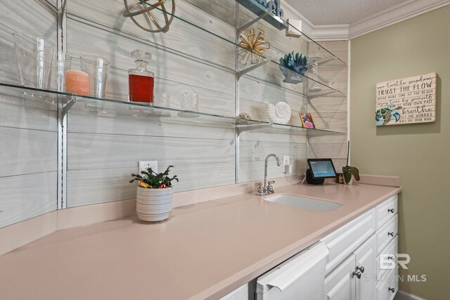 interior space featuring ornamental molding, sink, a textured ceiling, white cabinetry, and dishwasher