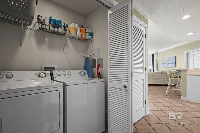 washroom featuring ornamental molding, light tile patterned floors, separate washer and dryer, and a textured ceiling