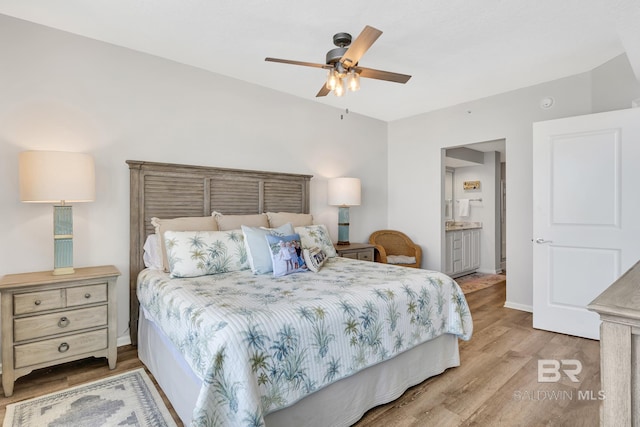 bedroom featuring a ceiling fan, ensuite bath, baseboards, and wood finished floors