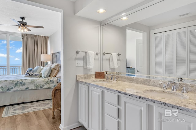 ensuite bathroom with a sink, visible vents, connected bathroom, and wood finished floors