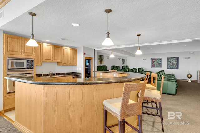 kitchen with light carpet, open floor plan, stainless steel appliances, a textured ceiling, and a sink