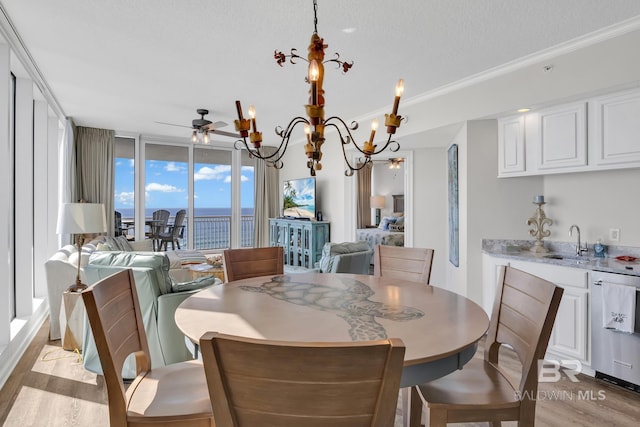 dining room with light wood-style floors, ornamental molding, a textured ceiling, and ceiling fan with notable chandelier