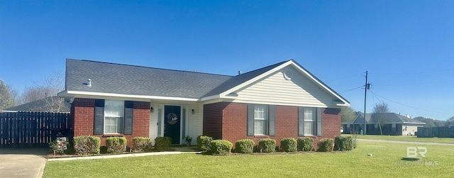 view of front of property with brick siding, driveway, a front yard, and fence