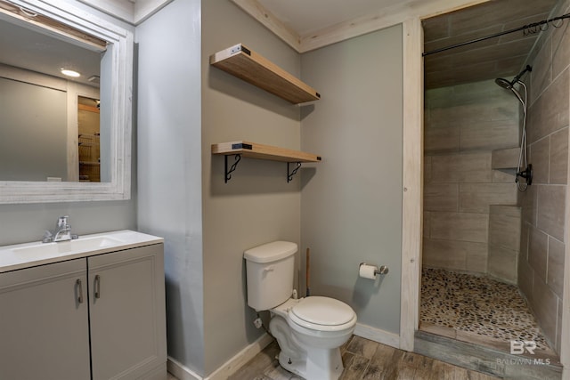 bathroom with toilet, a tile shower, vanity, and hardwood / wood-style floors