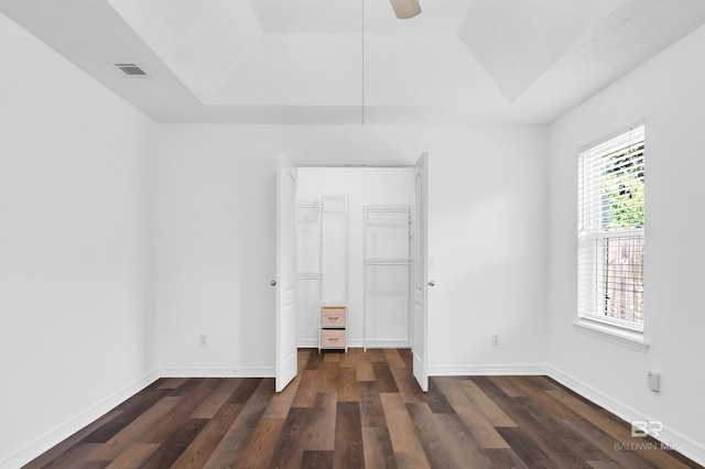 6950 Summerset Dr, Gulf Shores, AL 36542 - unfurnished bedroom featuring a raised ceiling, a walk in closet, and dark wood-style flooring