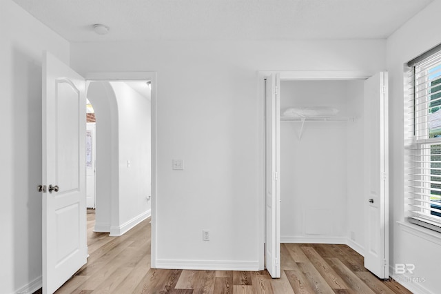 6950 Summerset Dr, Gulf Shores, AL 36542 - unfurnished bedroom with arched walkways, wood finished floors, a closet, and baseboards