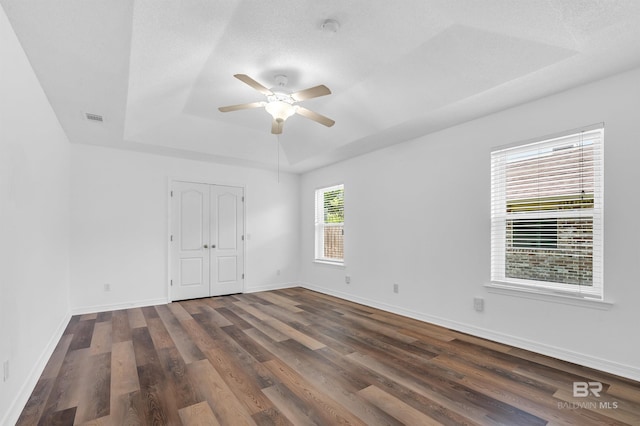 6950 Summerset Dr, Gulf Shores, AL 36542 - unfurnished bedroom with a tray ceiling, dark wood finished floors, baseboards, and ceiling fan