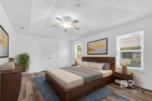 6950 Summerset Dr, Gulf Shores, AL 36542 - bedroom featuring a tray ceiling, wood finished floors, baseboards, and ceiling fan