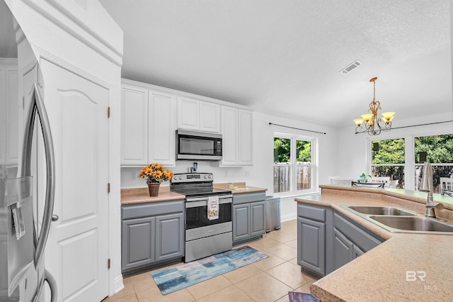 6950 Summerset Dr, Gulf Shores, AL 36542 - kitchen with stainless steel appliances, gray cabinets, a sink, a chandelier, and decorative light fixtures