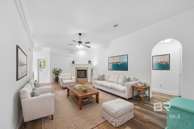 6950 Summerset Dr, Gulf Shores, AL 36542 - living area featuring light wood finished floors, a glass covered fireplace, a ceiling fan, baseboards, and arched walkways