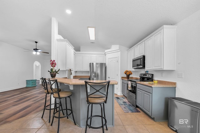 6950 Summerset Dr, Gulf Shores, AL 36542 - kitchen with appliances with stainless steel finishes, a peninsula, white cabinets, a kitchen breakfast bar, and a ceiling fan