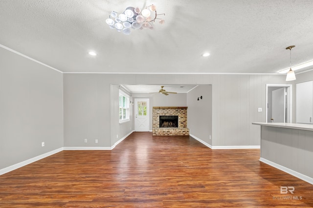 unfurnished living room featuring a textured ceiling, crown molding, ceiling fan, baseboards, and dark wood-style flooring