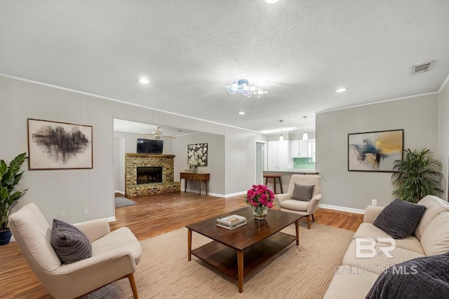 living area with visible vents, light wood-style floors, crown molding, and recessed lighting