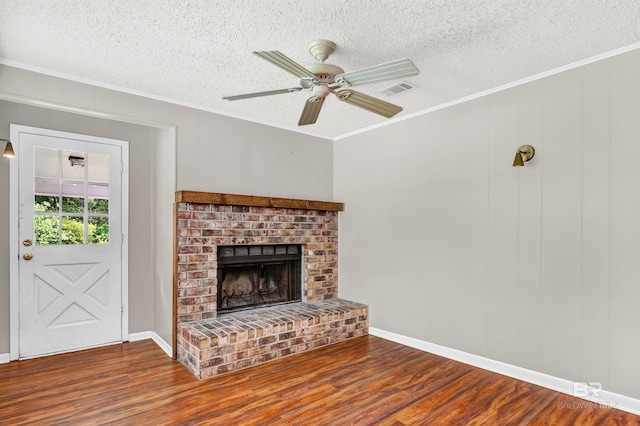 unfurnished living room featuring a textured ceiling, wood finished floors, crown molding, and visible vents